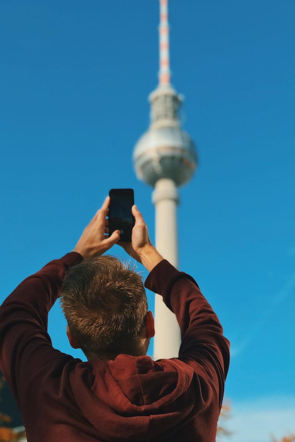 a_man_in_brown_jacket_taking_photo_of_the_tower_un